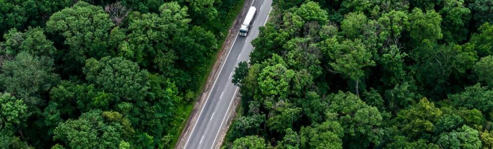 overhead view of Neste biofuel tanker driving through densely wooded area