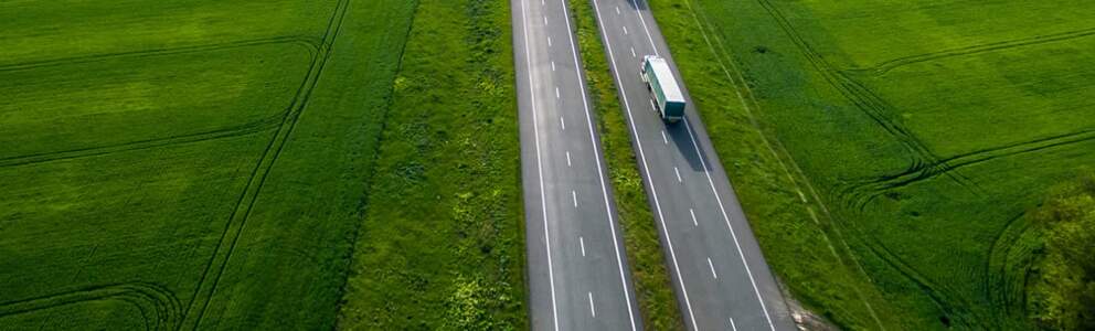 bird’s eye view of freight truck using renewable diesel to drive across green farm land